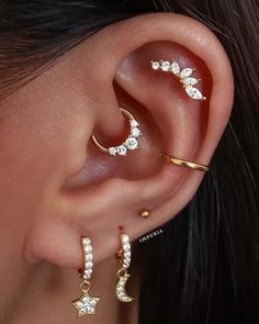 a woman wearing three different ear piercings with stars and moon designs on the side