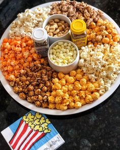 a plate filled with popcorn, peanuts and other snacks