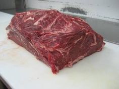 a piece of raw meat sitting on top of paper next to a knife and fork