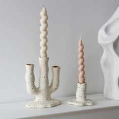 two white vases sitting on top of a shelf next to each other with candles in them