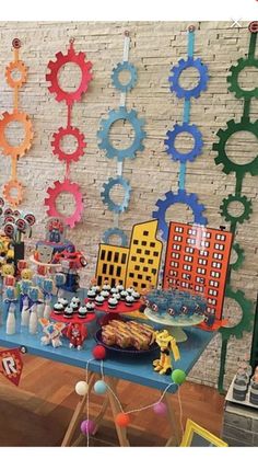 a table topped with lots of food and cupcakes next to a wall covered in gears