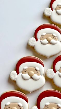 decorated cookies with santa claus faces and beards are arranged in rows on a white surface