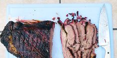 two pieces of meat on a blue plate with a knife and fork next to it