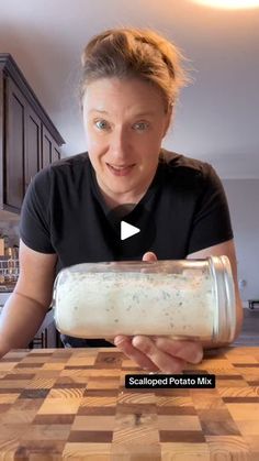 a woman is holding a jar full of food