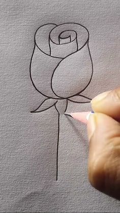 someone is drawing a rose on the paper