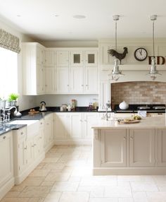 a large kitchen with white cabinets and black counter tops, along with a clock on the wall