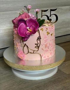 a pink and gold decorated cake with flowers on the top is sitting on a plate