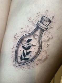 a woman's thigh with a bottle filled with plants and leaves on the side