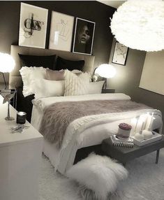 a white bed sitting in a bedroom next to two lamps and pictures on the wall