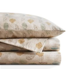 two pillows stacked on top of each other next to one another with leaves printed on them