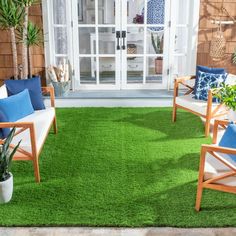 an outdoor area with green grass and wooden chairs, potted plants on the patio