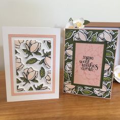 two cards with flowers on them are sitting on a table next to each other,