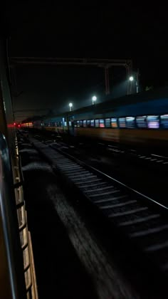 a train traveling down tracks at night with lights on and no people in the background