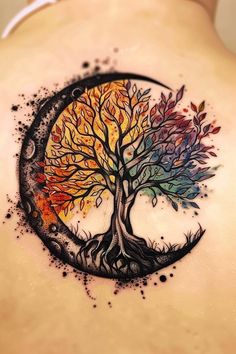 a woman's back with a tree and moon tattoo on it