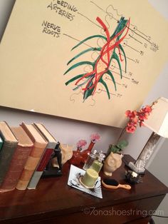 a wooden table topped with lots of books next to a lamp and painting on the wall