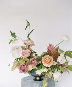 a vase filled with lots of flowers sitting on top of a blue table next to a white wall