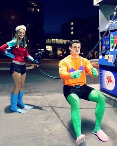 two people in costumes are sitting on the ground near a vending machine at night