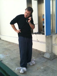 a man standing on the sidewalk while talking on his cell phone