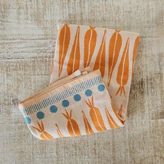 two orange and blue carrots on a white background, one has a zippered pouch