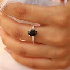 a woman's hand with a ring on it and a black stone in the middle