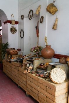 there are many pots and pans on the table in front of this wall that is made out of bricks