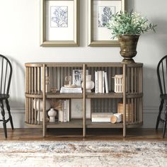 two chairs and a book shelf in a room with pictures on the wall behind them