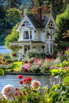 a white house sitting on top of a lush green field next to a body of water