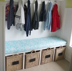 a coat rack with baskets and coats hanging from it's hooks on the wall