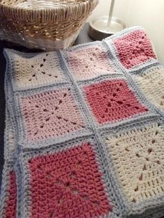 a crocheted blanket sitting on top of a table next to a basket