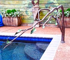 a statue sitting on top of a pool next to a tree branch with leaves growing out of it