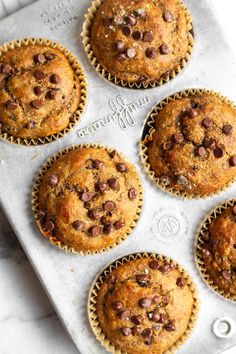 freshly baked chocolate chip muffins in a baking pan on a marble countertop