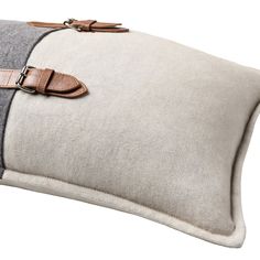 a gray and white pillow with two leather straps on the front, along with a brown buckle