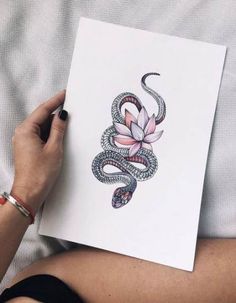 a woman holding up a piece of paper with an image of a snake on it