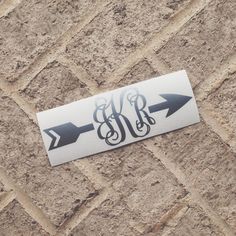 an arrow sticker on the side of a brick wall with monogrammed letters