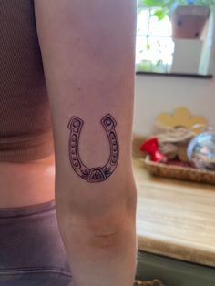 a woman with a tattoo on her arm that has a horseshoe in the middle of it