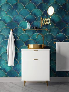 a bathroom with blue and green wallpaper, gold faucet and white cabinet