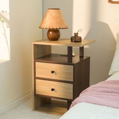 a nightstand with two drawers next to a bed