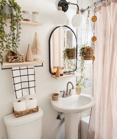 a white sink sitting under a bathroom mirror next to a toilet and bathtub covered in plants