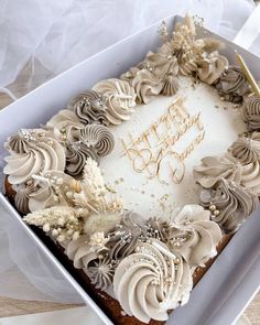 a birthday cake with white frosting and brown icing in a box on a table