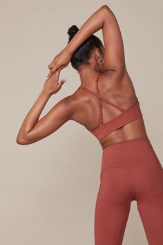 a woman with her back to the camera, wearing a red sports bra top and leggings