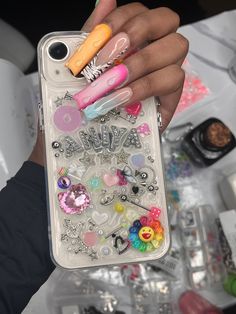 a person holding a phone case with lots of nail polish and accessories on top of it