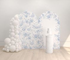 there is a white spray bottle next to a blue and white wall with flowers on it