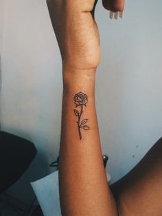 a woman's arm with a small rose tattoo on the left side of her wrist