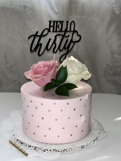 there is a pink cake with two roses on it and the word hello thirty spelled in black