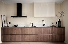 a kitchen with wooden cabinets and white counter tops, black appliances and vases on the counters