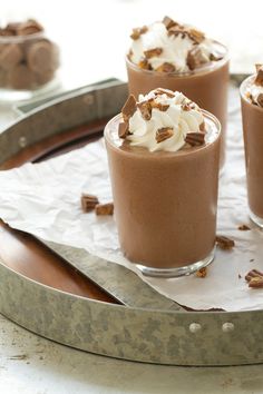 three glasses filled with dessert sitting on top of a tray