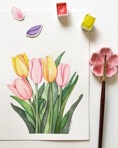 watercolor painting of pink and yellow tulips on white paper next to paintbrush