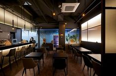 an empty restaurant with tables and chairs in front of a bar area that is lit up at night