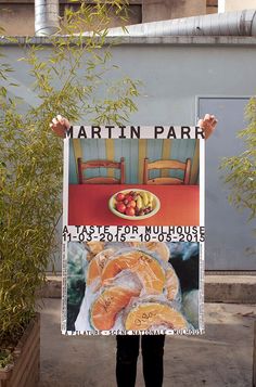 a person holding up a sign in front of a building that says martin park on it