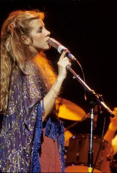 a woman with long hair singing into a microphone